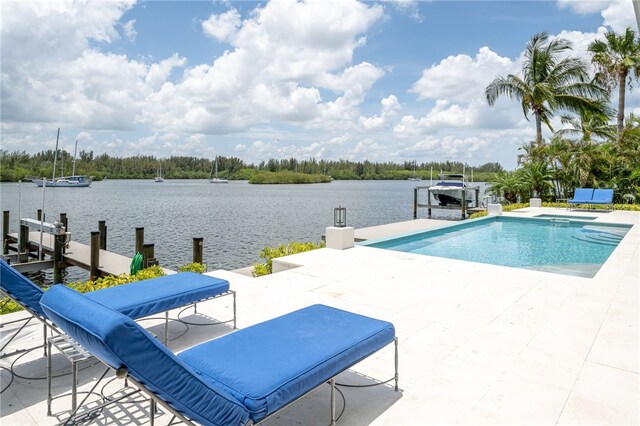 view of swimming pool with a boat dock, a patio, and a water view