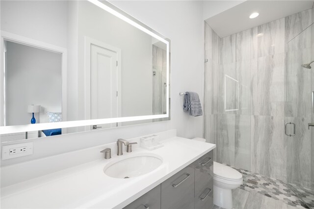 bathroom with vanity, a shower with shower door, and toilet