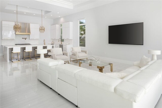 living room featuring a tray ceiling, sink, and an inviting chandelier