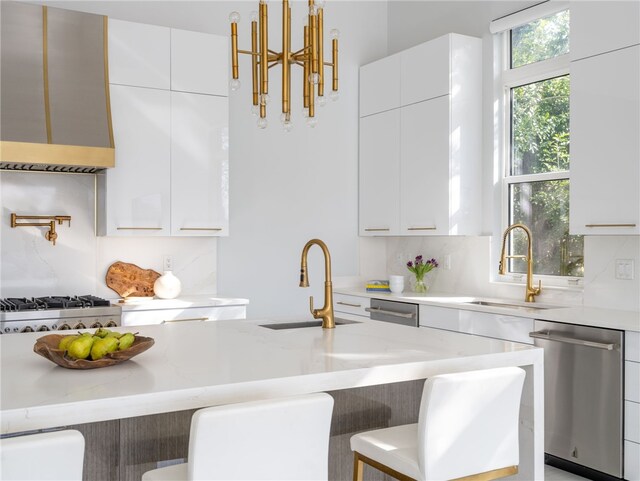 kitchen with a kitchen bar, stainless steel dishwasher, exhaust hood, pendant lighting, and white cabinetry