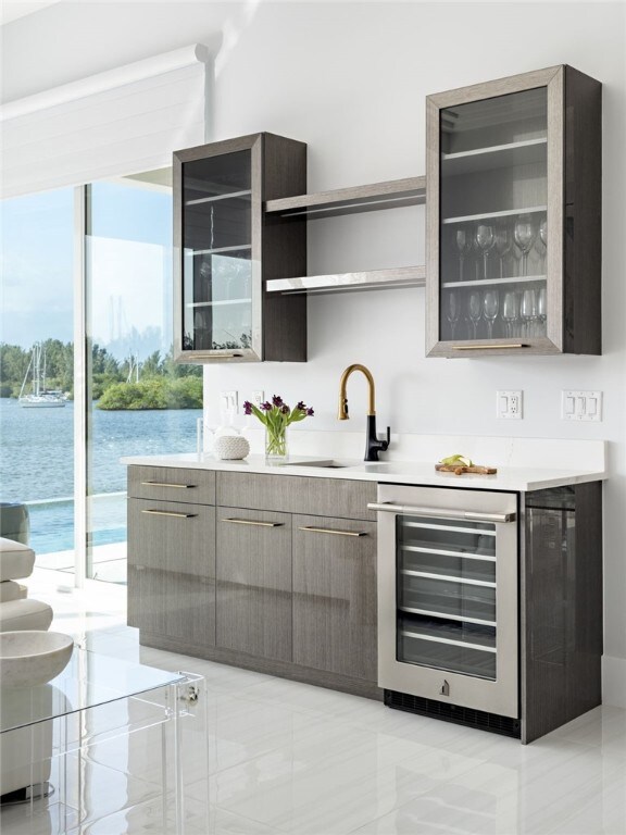 bar with sink, a water view, and beverage cooler