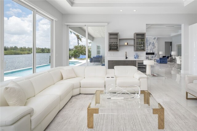 living room with wine cooler, a water view, and indoor bar