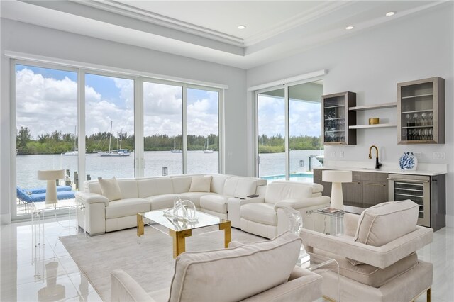 living room featuring wine cooler, a water view, ornamental molding, and indoor wet bar