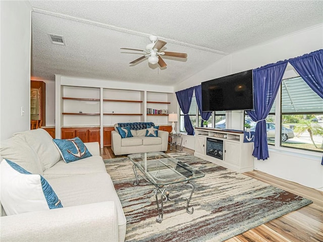 living room featuring hardwood / wood-style flooring, vaulted ceiling, ceiling fan, and a textured ceiling