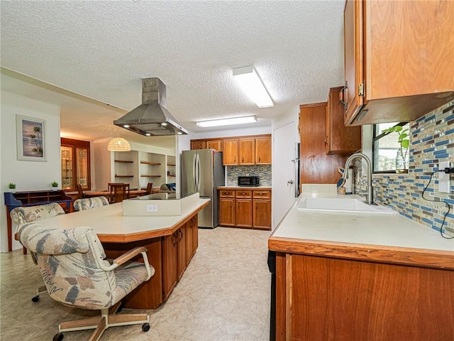 kitchen with island range hood, stainless steel refrigerator, tasteful backsplash, sink, and a textured ceiling