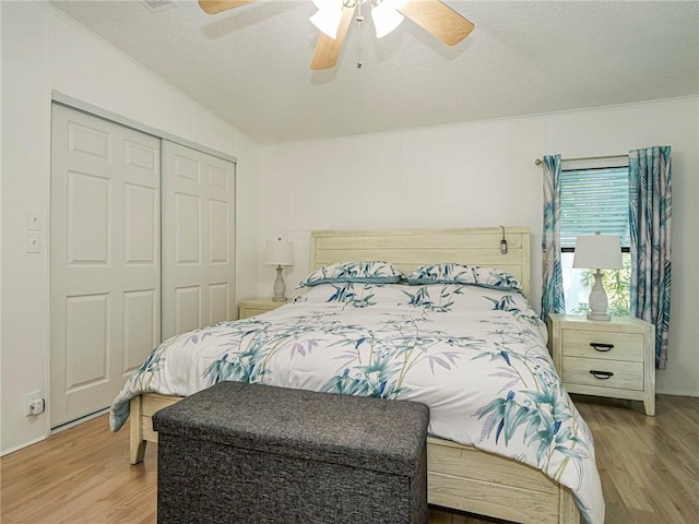 bedroom featuring ceiling fan, light hardwood / wood-style floors, a closet, and a textured ceiling