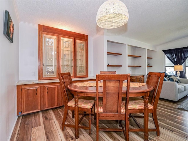 dining area with an inviting chandelier, light hardwood / wood-style floors, and a textured ceiling