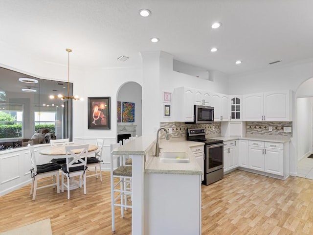 kitchen featuring sink, hanging light fixtures, stainless steel appliances, a kitchen breakfast bar, and kitchen peninsula