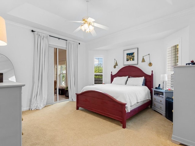 bedroom with light carpet, a tray ceiling, ceiling fan, and crown molding