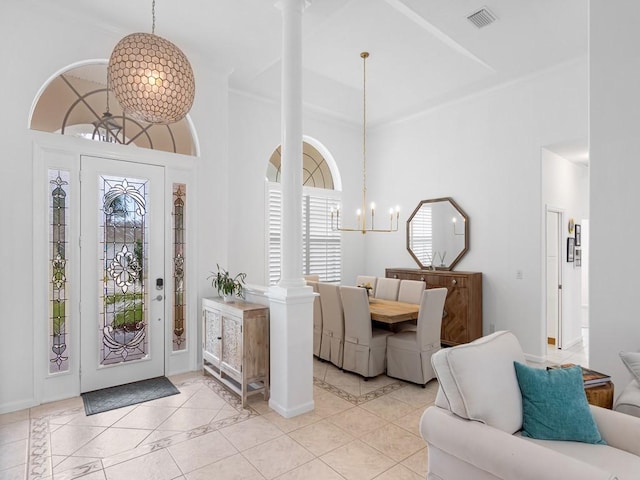 tiled foyer with decorative columns, a towering ceiling, and a chandelier