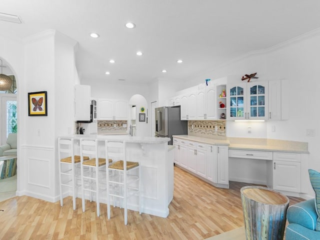 kitchen with high quality fridge, white cabinetry, and crown molding