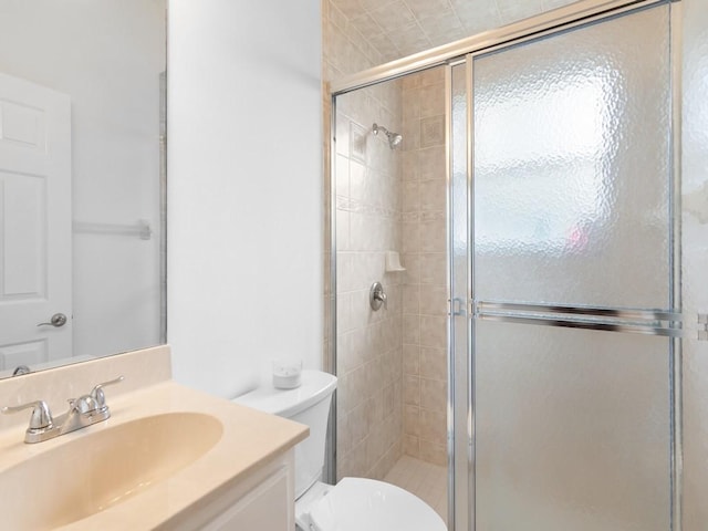 bathroom with a shower with door, vanity, and toilet