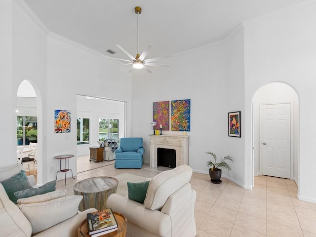 tiled living room featuring ceiling fan, crown molding, and a towering ceiling