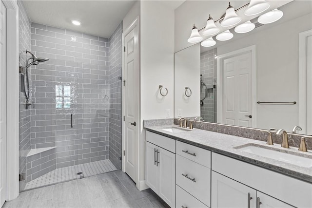 bathroom featuring double vanity, a stall shower, and a sink