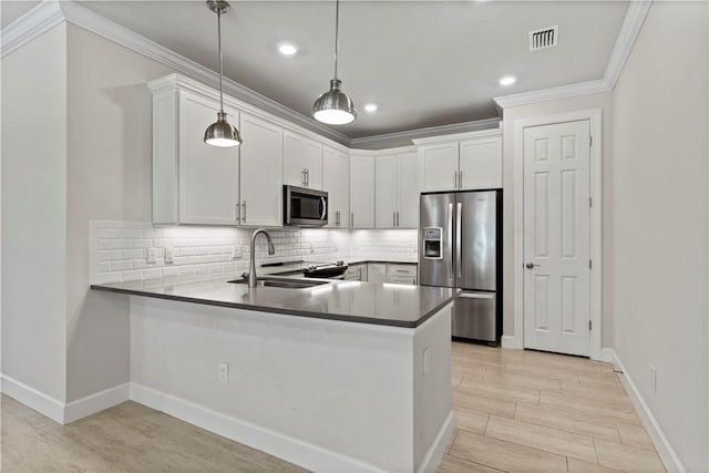 kitchen featuring a peninsula, a sink, ornamental molding, stainless steel appliances, and backsplash