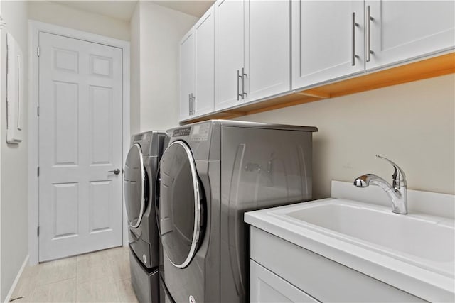 laundry room featuring cabinet space, separate washer and dryer, and a sink