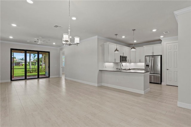 kitchen with open floor plan, decorative backsplash, appliances with stainless steel finishes, a peninsula, and white cabinets