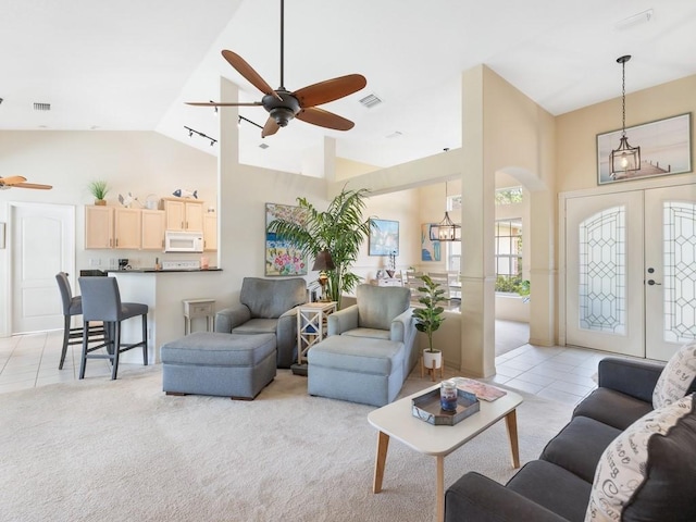 tiled living room featuring ceiling fan, french doors, and high vaulted ceiling