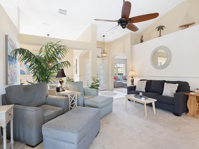 living room with ceiling fan with notable chandelier, high vaulted ceiling, and light carpet