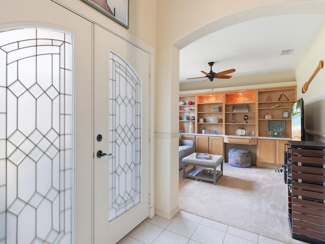 foyer with french doors, ceiling fan, and light carpet