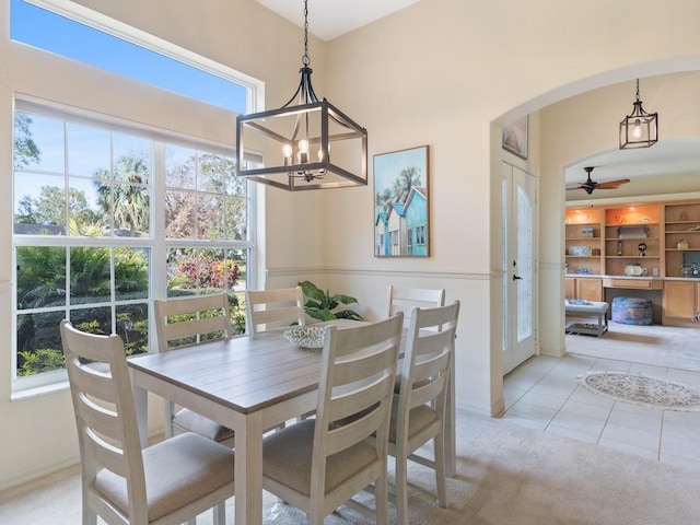 dining area featuring light tile patterned flooring and ceiling fan with notable chandelier