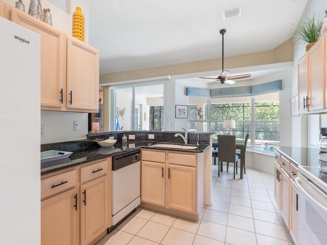 kitchen with white appliances, kitchen peninsula, ceiling fan, dark stone counters, and sink