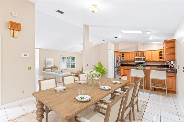 dining room featuring high vaulted ceiling, light tile patterned flooring, and sink