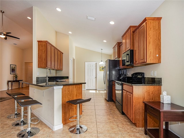 kitchen with a breakfast bar, appliances with stainless steel finishes, kitchen peninsula, decorative light fixtures, and vaulted ceiling