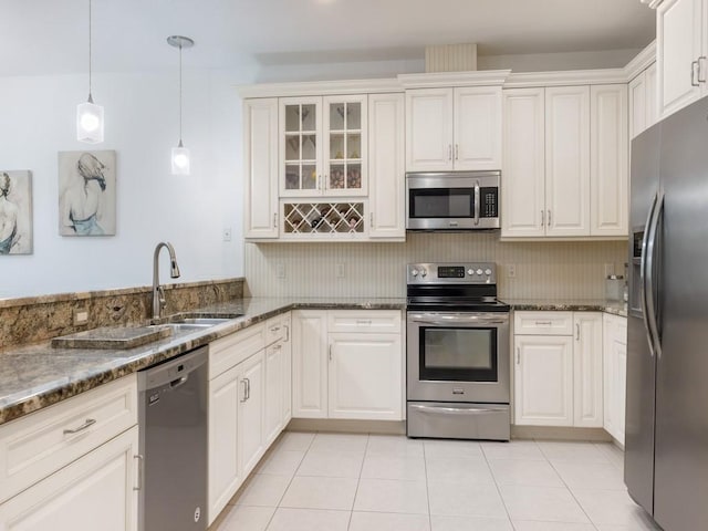 kitchen with stainless steel appliances, pendant lighting, white cabinets, and dark stone countertops