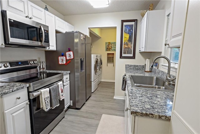 kitchen with white cabinetry, sink, appliances with stainless steel finishes, and washing machine and clothes dryer