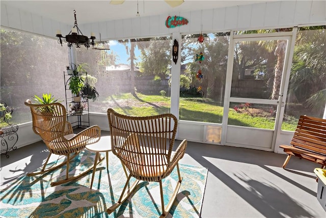 sunroom / solarium featuring ceiling fan with notable chandelier