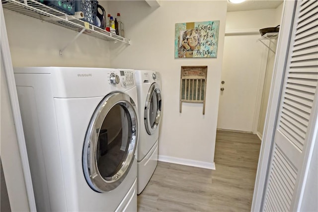 clothes washing area featuring washer and dryer and light hardwood / wood-style flooring