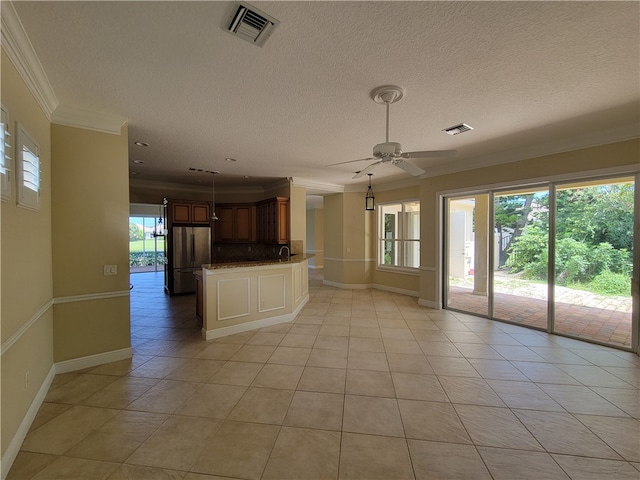 kitchen with kitchen peninsula, ceiling fan, crown molding, light tile patterned floors, and stainless steel refrigerator