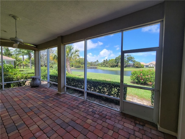 unfurnished sunroom with ceiling fan, a water view, and a healthy amount of sunlight