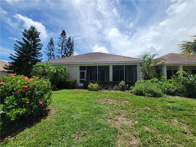 rear view of house featuring a sunroom and a lawn