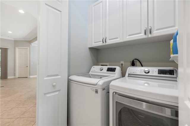 laundry area featuring ornamental molding, light tile patterned flooring, cabinets, and washer and dryer