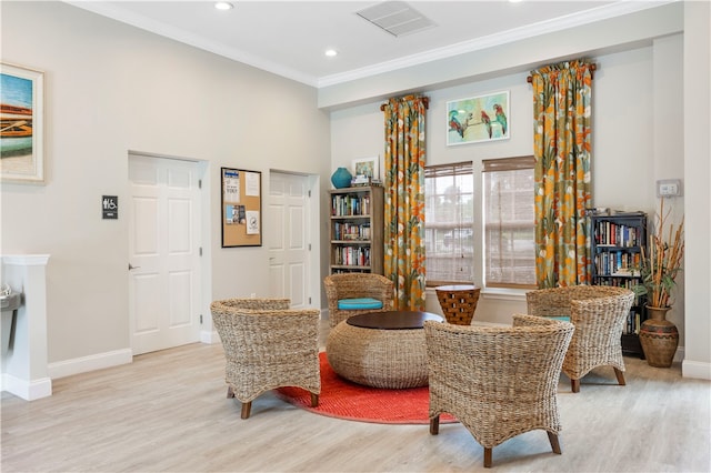 living area with crown molding and light hardwood / wood-style flooring