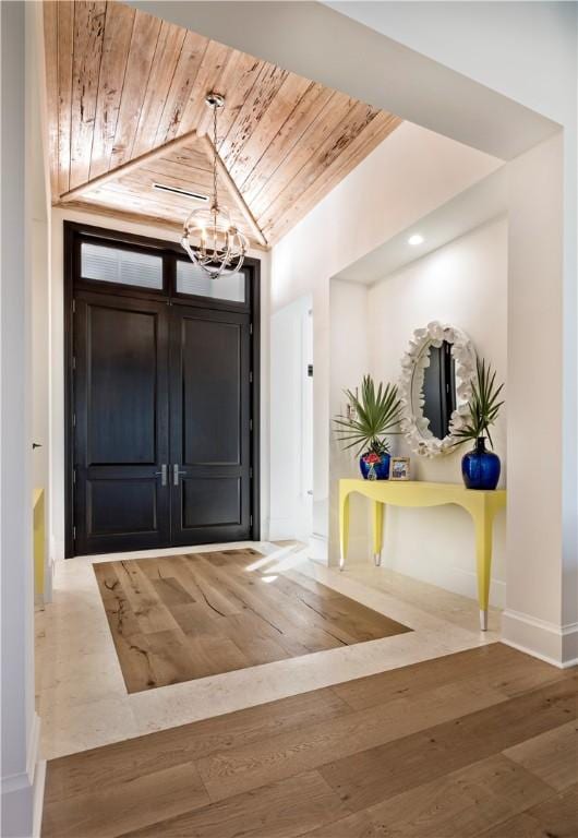 entrance foyer featuring wood ceiling, lofted ceiling, an inviting chandelier, and wood-type flooring