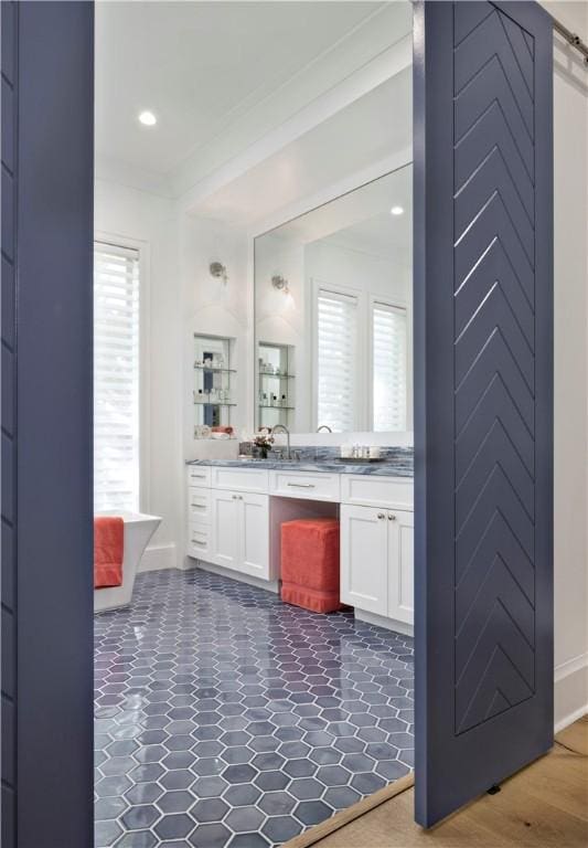 bathroom featuring ornamental molding, vanity, a bathtub, and a wealth of natural light