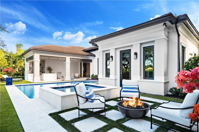 rear view of house with a pool with hot tub, a patio area, and an outdoor fire pit