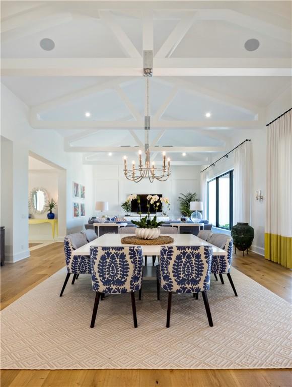 dining area with beamed ceiling, a chandelier, and light hardwood / wood-style flooring