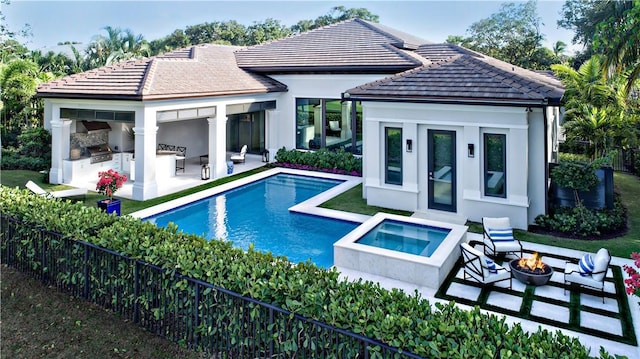 back of house featuring a patio area, area for grilling, an outbuilding, a pool with hot tub, and a fire pit