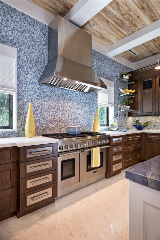 kitchen featuring tasteful backsplash, double oven range, dark brown cabinets, wooden ceiling, and wall chimney exhaust hood