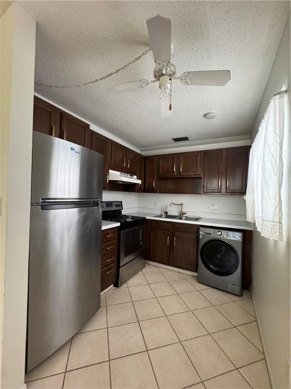5 Vista Palm Ln Unit 105, Vero Beach, FL 32962 - kitchen with appliances with stainless steel finishes, washer / dryer, under cabinet range hood, light countertops, and light tile patterned floors