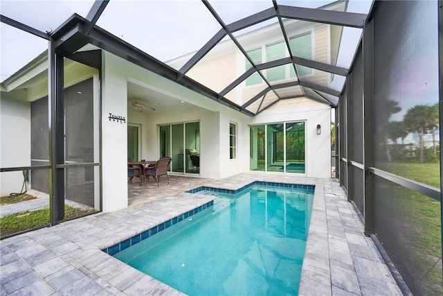 view of swimming pool featuring ceiling fan, glass enclosure, and a patio