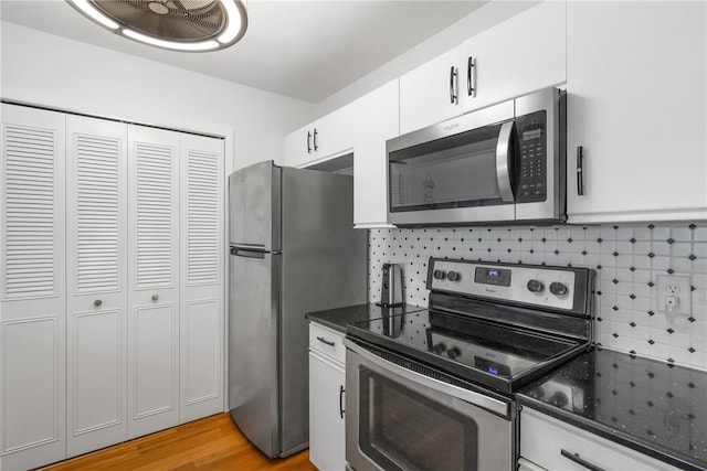 25 Plantation Dr Unit 206, Vero Beach, FL 32966 - kitchen featuring decorative backsplash, appliances with stainless steel finishes, light wood-type flooring, dark stone countertops, and white cabinetry