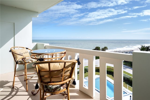 balcony featuring a view of the beach and a water view