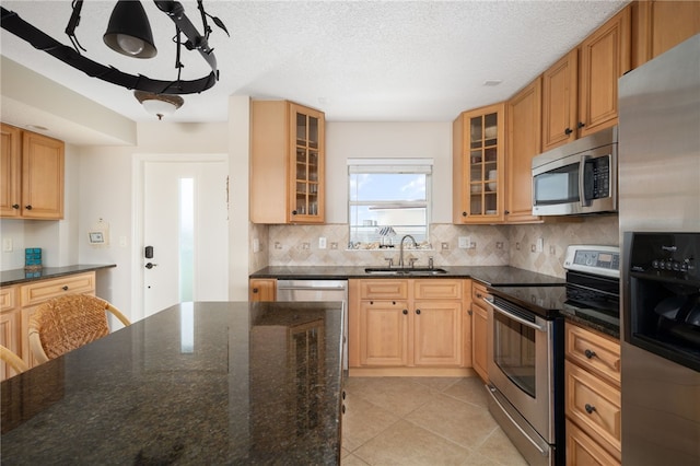 kitchen featuring appliances with stainless steel finishes, backsplash, dark stone counters, and sink