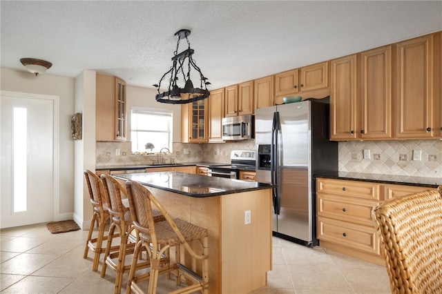 kitchen featuring sink, a center island, decorative light fixtures, light tile patterned floors, and appliances with stainless steel finishes