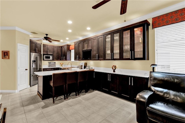 kitchen with ceiling fan, kitchen peninsula, a kitchen bar, high end fridge, and ornamental molding